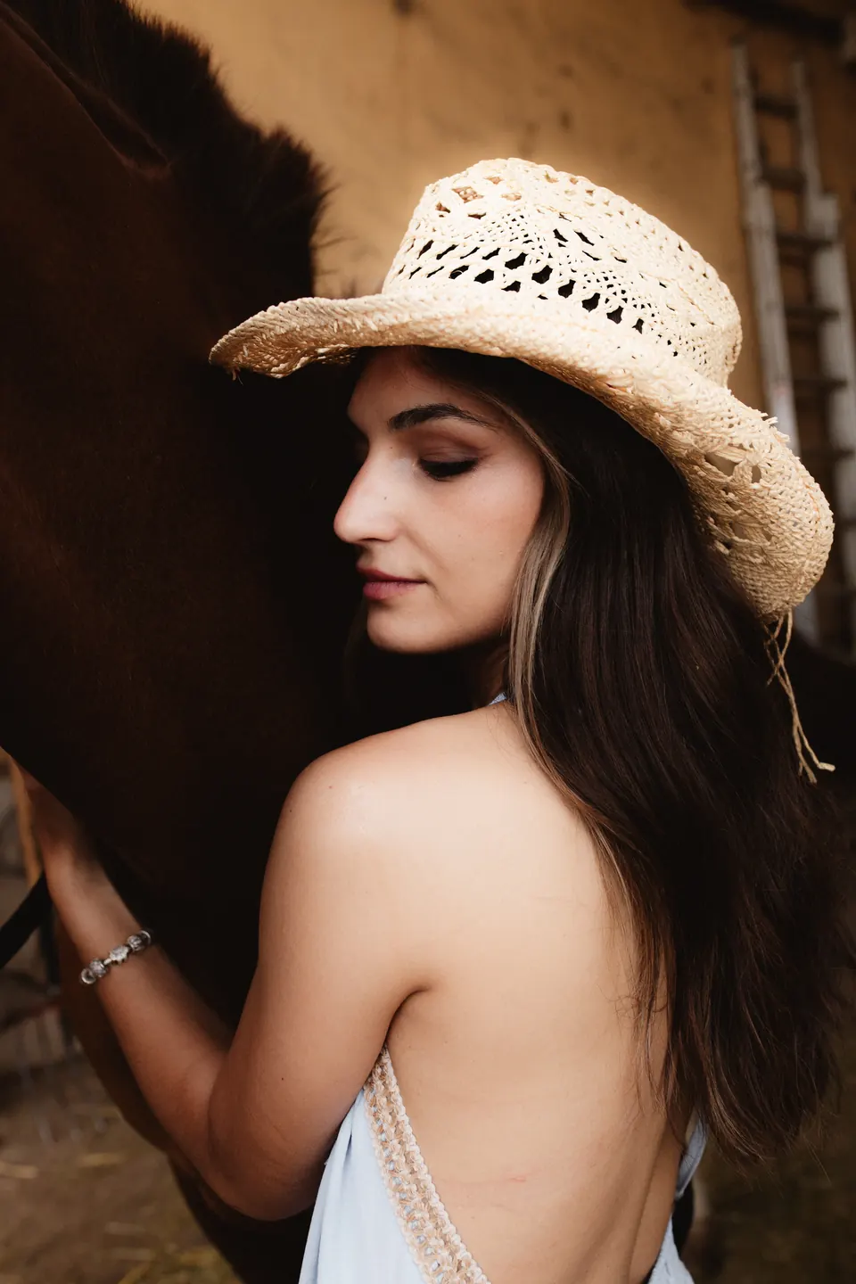 Editorial ecuestre: modelo de espaldas con sombrero de paja junto a un caballo