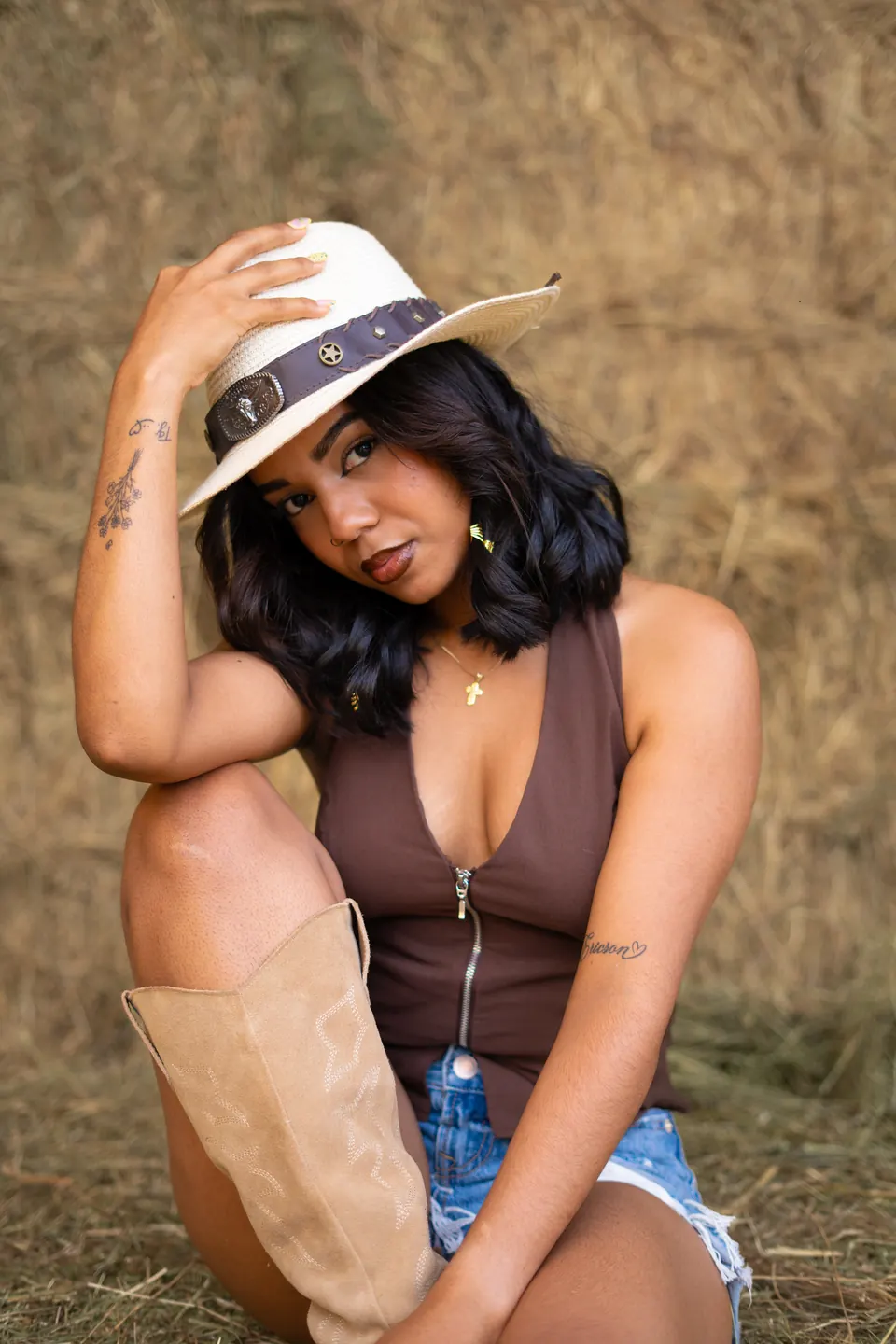 Editorial ecuestre: modelo con sombrero sentada sobre la paja