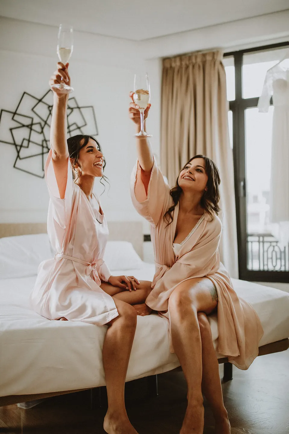La novia y una amiga brindando durante los preparativos