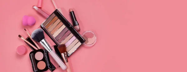Productos de maquillaje en fondo rosa colocados en modo presentación desordenada