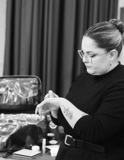 a woman in glasses applying a makeup product