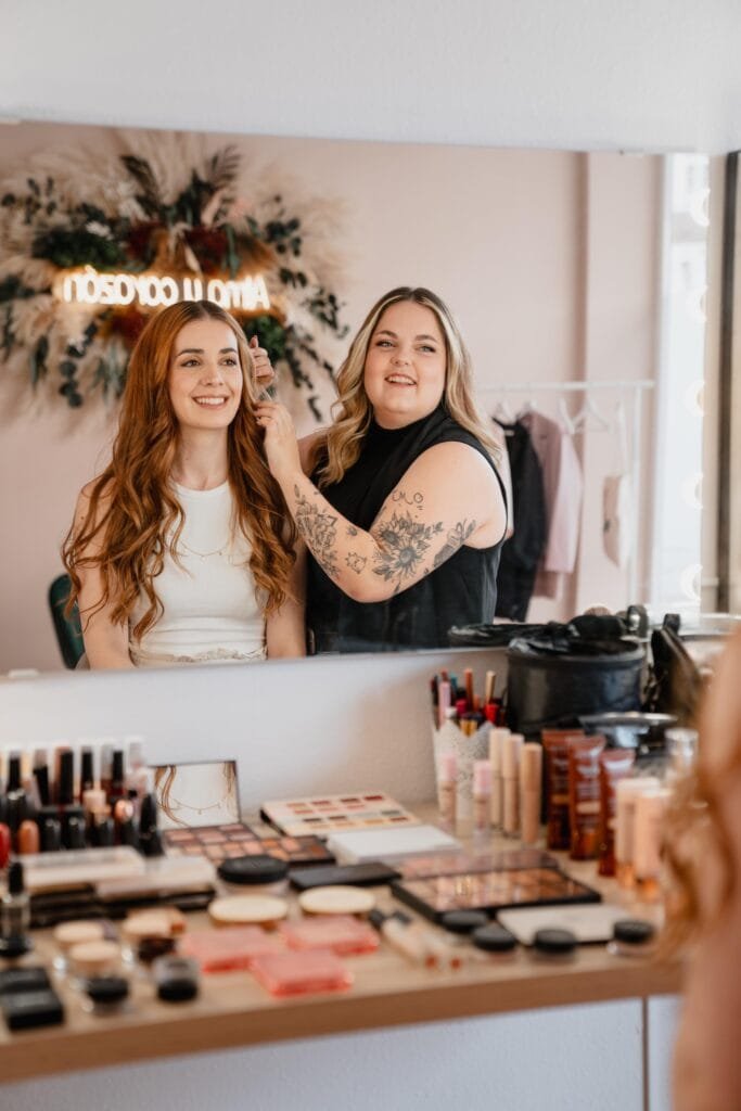 a woman getting her hair done by a woman in a mirror